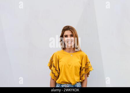 Porträt einer hübschen lächelnden blonden Frau an der Wand Stockfoto