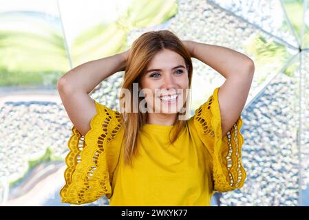Dieses fesselnde Bild zeigt eine junge Frau mit einem strahlenden Lächeln, gekleidet in einem leuchtend gelben Oberteil mit komplizierten Ärmeldetails und einem klassischen Jeansski Stockfoto