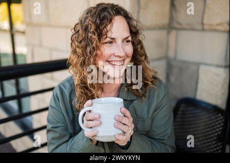 Frau lächelt mit Kaffeetasse Stockfoto