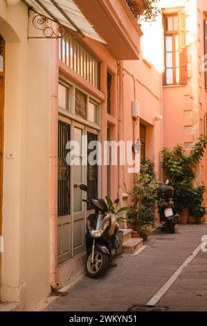 Motorräder parken in einem rosafarbenen Gebäude in einer Gasse auf Kreta, Griechenland Stockfoto