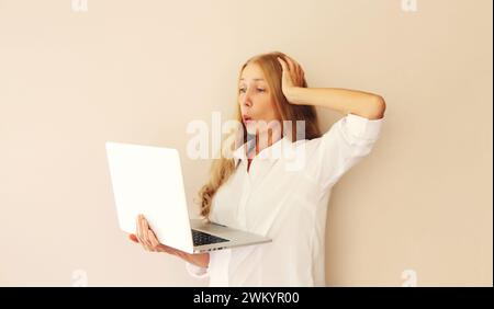 Überraschte Frau mittleren Alters, die zu Hause auf den Laptop schaut Stockfoto