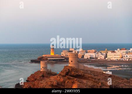 Westlicher Teil der Stadt Sur mit Al-Ayjah Lighthouse und Al-Ayjah Castle in goldener Stunde, Oman. Blick vom Höhepunkt der Stadt Sur Stockfoto