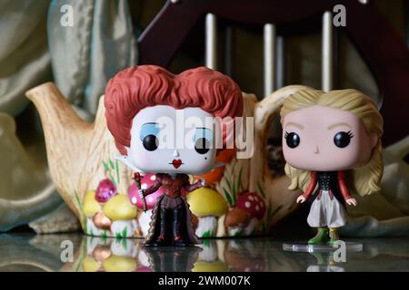 Funko Pop Actionfiguren von Red Queen und Alice im Wunderland. Bunte Teekanne, fabelhafter Palast, Säulen, Spiegelboden, grüner Vorhang, Fantasie. Stockfoto