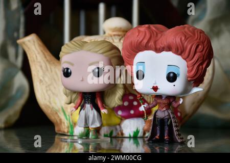 Funko Pop Actionfiguren von Red Queen und Alice im Wunderland. Bunte Teekanne, fabelhafter Palast, Säulen, Spiegelboden, grüner Vorhang, Fantasie. Stockfoto