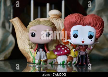 Funko Pop Actionfiguren von Red Queen und Alice im Wunderland. Bunte Teekanne, fabelhafter Palast, Säulen, Spiegelboden, grüner Vorhang, Fantasie. Stockfoto