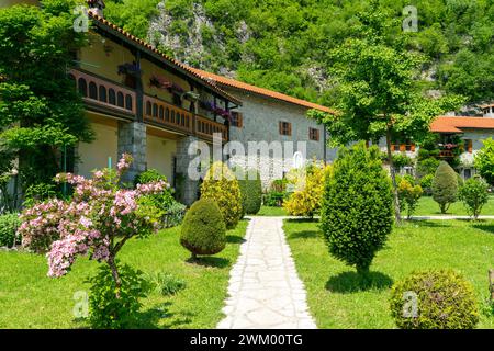 Malerischer Hof des Klosters von Moraca mit grünen Rasen, Blumen und Gebäuden mit roten Ziegeldächern vor blauem Himmel, Montenegro Stockfoto