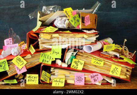 Unordentliches Aktenmappe, klebrige Notizen und alte Papiere auf einem unordentlichen, chaotischen Schreibtisch. Bürokratie, Bürokratie, überarbeitet, Burnout, Ausbeutung, unordentliches Büro Stockfoto