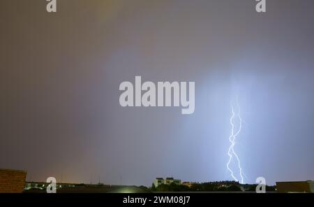 Spektakulärer Sturm und Blitz erleuchten den Himmel und treffen auf eines der Gebäude in einer Stadt. Torrejon de Ardoz. Stockfoto