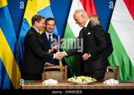 Budapest, Ungarn. Februar 2024. Göran Martensson (l), Generaldirektor der schwedischen Wehrmaterialverwaltung, und ungarischer Verteidigungsminister Kristof Szalay-Bobrovniczky schütteln die Hand, nachdem sie den Vertrag während einer gemeinsamen Pressekonferenz in Budapest unterzeichnet hatten. Im Hintergrund stehen der schwedische Premierminister Ulf Kristersson (l) und der ungarische Premierminister Viktor Orban. Kurz vor der erwarteten Zustimmung Ungarns zum NATO-Beitritt Schwedens haben sich die beiden Länder auf ein umfassendes Rüstungsabkommen geeinigt. Quelle: Marton Monus/dpa/Alamy Live News Stockfoto