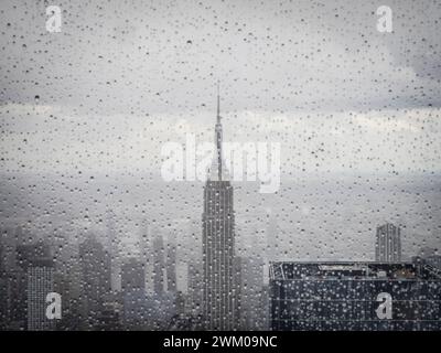 Das Empire State Building im Regen, durch ein Fenster mit Regentropfen gesehen Stockfoto