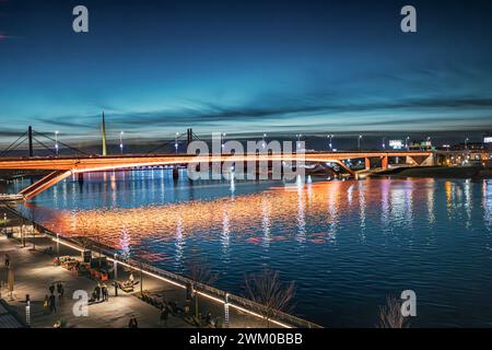 02 Januar 2024, Belgrad, Serbien: Herrlicher Sonnenuntergang über der Save in Belgrad, Serbien, leuchtende Brücke und umliegende Stadtlandschaft Stockfoto