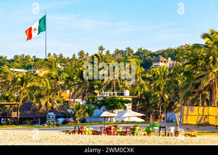 Puerto Escondido Oaxaca Mexiko 16. November 2022 Palmen People Sonnenschirme und Sonnenliegen im Beach Resort Hotel auf tropischem mexikanischem B Stockfoto