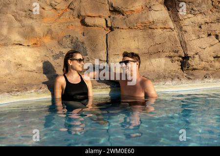 Ein lächelndes Paar, das sich im Spa-Swimmingpool entspannt. Romantischer Kurzurlaub Stockfoto