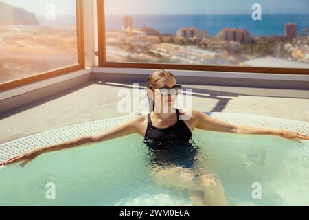 Frau, die sich am sonnigen Tag im Teneriffa-Ferienresort im Whirlpool auf dem Dach erholt. Kurzurlaub Stockfoto