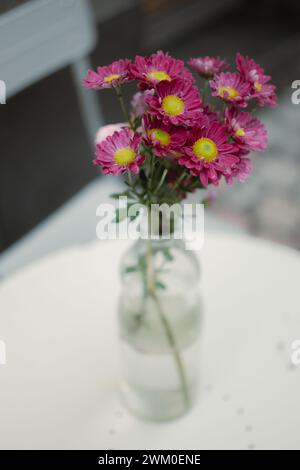 Rosa Blumen in einer Glasvase auf einer Tischdecke Stockfoto