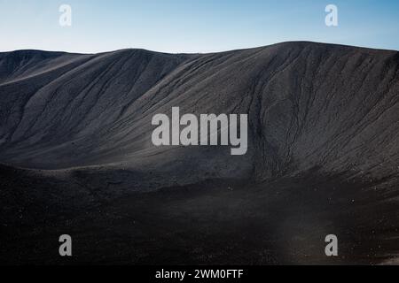 Dunkler Sand als Hintergrund, schwarze vulkanische Sandwellen Textur, Nahaufnahme aus der Luft. Naturmuster-Konzept. Stockfoto