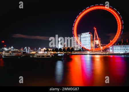 Ein großes beleuchtetes Riesenrad vor einem Hintergrund farbenfroher Lichter, London, Großbritannien Stockfoto