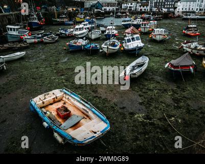 Viele Boote legten an Sandstrand in der Nähe von Gebäuden in einem Hafen in Mevagissey, Großbritannien, an Stockfoto