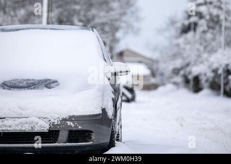 Schneehaufen auf der Straße, ungesäuerte Straßen, Autos parkten am Straßenrand. Stockfoto