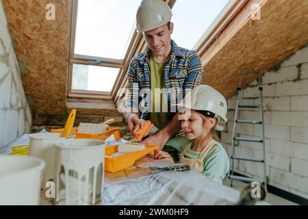 Tochter hilft Vater im Zimmer, das gerade renoviert wird Stockfoto