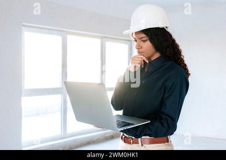 Architekt trägt Helm mit Laptop vor Ort Stockfoto