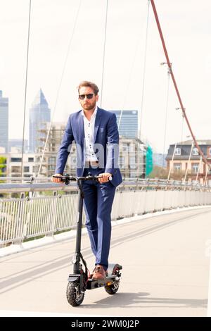 Geschäftsmann, der einen elektrischen Roller auf der Brücke in der Stadt fährt Stockfoto