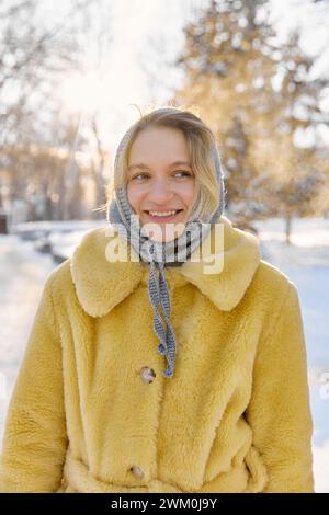 Lächelnde junge Frau mit Kopftuch und Pelzmantel im Winter Stockfoto