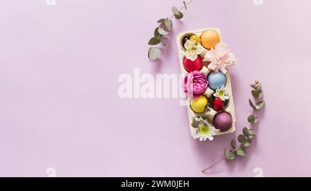 Farbenfrohe Ostereier mit Blumen auf rosa Hintergrund Stockfoto