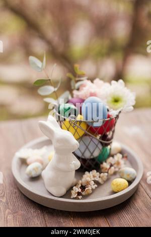 Osterdekoration mit Eiern und Blumen im Korb auf Tablett Stockfoto