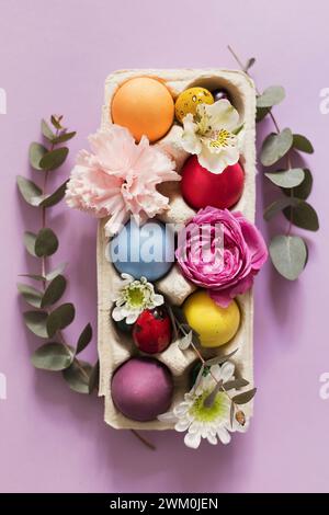 Farbenfrohe Ostereier mit Blumen auf rosa Hintergrund Stockfoto