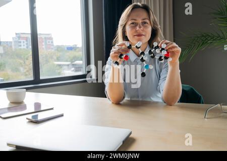 Wissenschaftler, der molekulare Strukturen am Schreibtisch im Büro hält Stockfoto