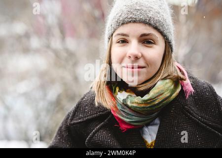 Lächelnde junge Frau mit Strickmütze im Winter Stockfoto