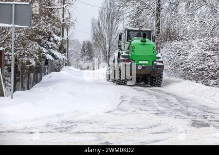 Traktor räumt Schnee auf der Straße nach starkem Schneefall, Straßenwartung im Winter. Stockfoto