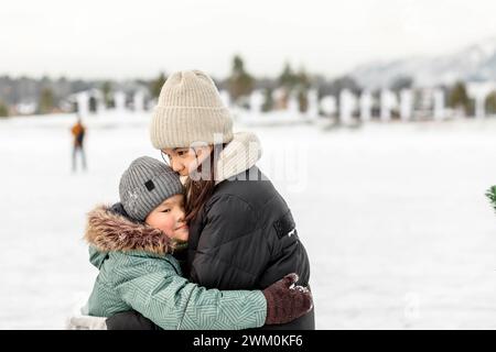 Bruder umarmt Schwester und trägt warme Kleidung im Winter Stockfoto