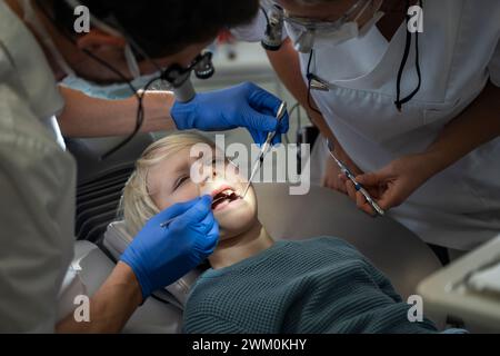 Zahnarzt untersucht die Zähne des Patienten in der Nähe eines Assistenten in der Klinik Stockfoto