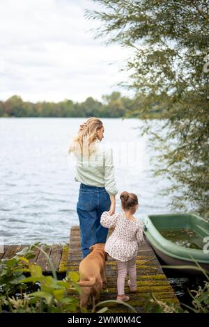 Mutter und Tochter gehen mit Hund auf dem Steg Stockfoto