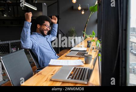 Erfolgreicher Geschäftsmann, der mit Laptops am Schreibtisch sitzt Stockfoto