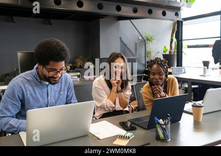 Glückliche Geschäftsfrauen und Geschäftsleute, die an Laptops arbeiten Stockfoto