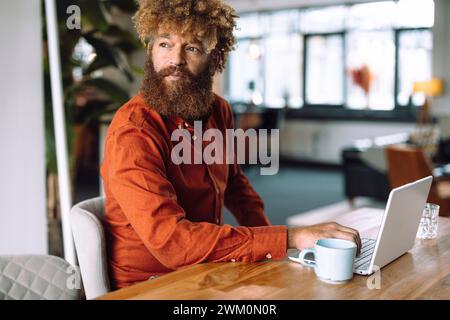 Geschäftsmann sitzt mit Laptop und Kaffeetasse im Büro Stockfoto