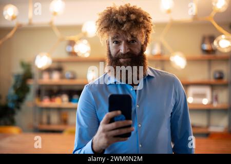 Reifer Geschäftsmann, der mit dem Smartphone steht Stockfoto