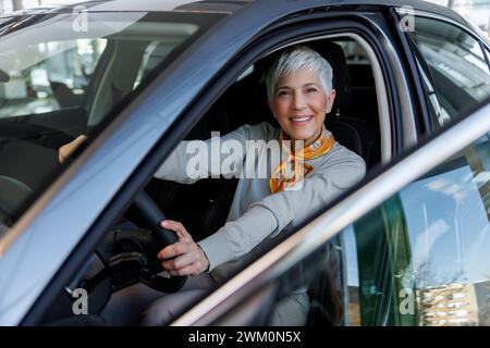 Glückliche Seniorin, die im Auto sitzt Stockfoto