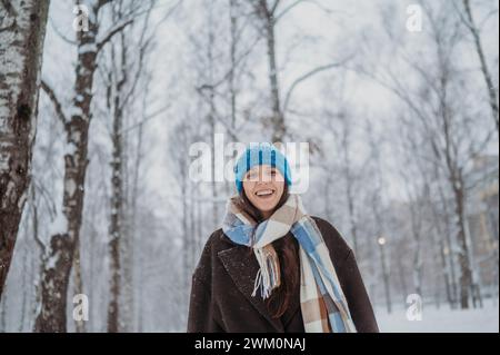 Lächelnde reife Frau in warmen Kleidern im Snowpark Stockfoto