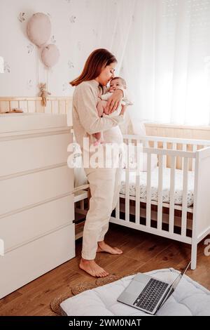 Mutter küsst ein kleines Mädchen in der Nähe des Kinderbetts zu Hause Stockfoto