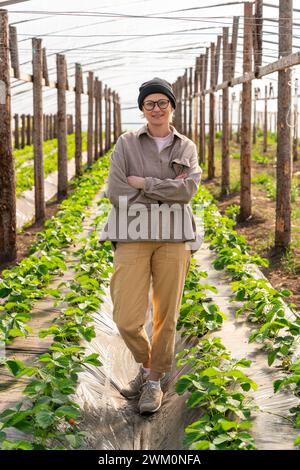 Selbstbewusster Landwirt, der mit überkreuzten Armen im Gewächshaus steht Stockfoto