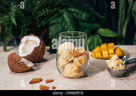 Mango- und Kokoseis im Glas in der Nähe von Servierlöffel Stockfoto