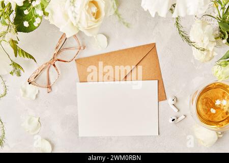 Ästhetische feminine flache Gläser, Teetasse und Ohrhörer mit handgefertigtem Papierumschlag für Grüße, Text zwischen weißen Blumen Stockfoto