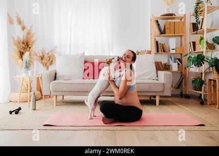 Eine glückliche schwangere Frau, die gern zu Hause Hunde leckt Stockfoto