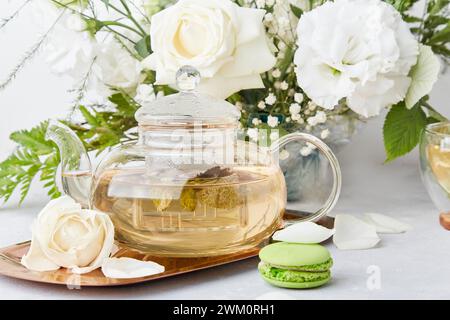 Ästhetische Tischaufstellung am Morgen. Grüner Tee, Makronen-Desserts, weißes Bouquet. Zeit für dich, langsam lebendes Konzept Stockfoto