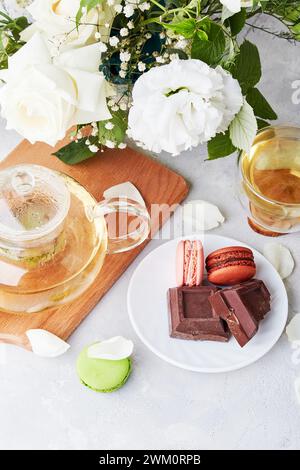 Ästhetischer Morgen. Grüner Tee, Makronen-Desserts, Schokolade, weißes Bouquet - Zeit für sich, langsam lebendiges Konzept Stockfoto