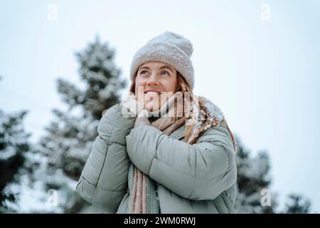 Lächelnde Frau in Jacke und Tag träumend im Winter Stockfoto